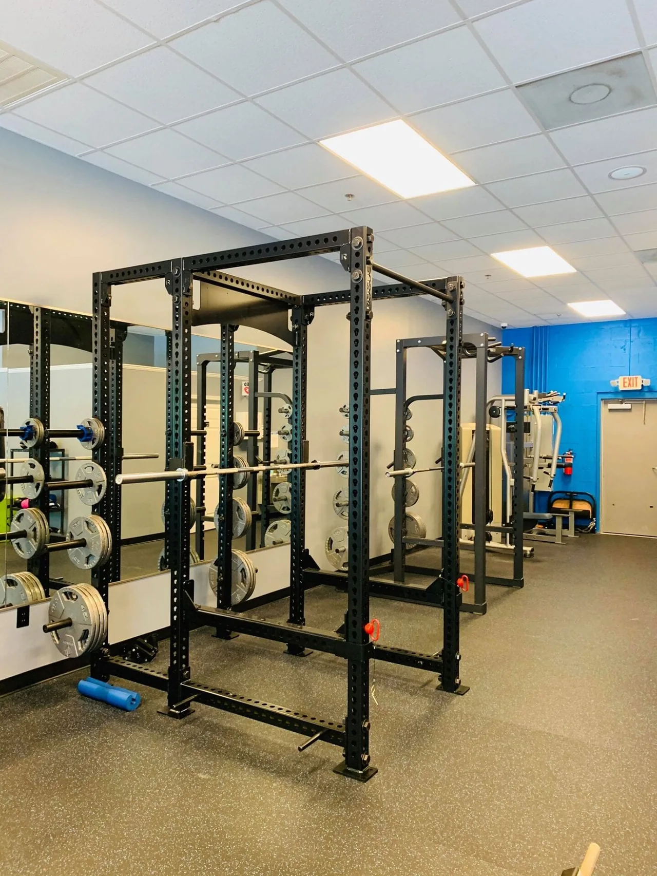 Two heavy-duty Rogue power racks loaded with Olympic plates and barbells.