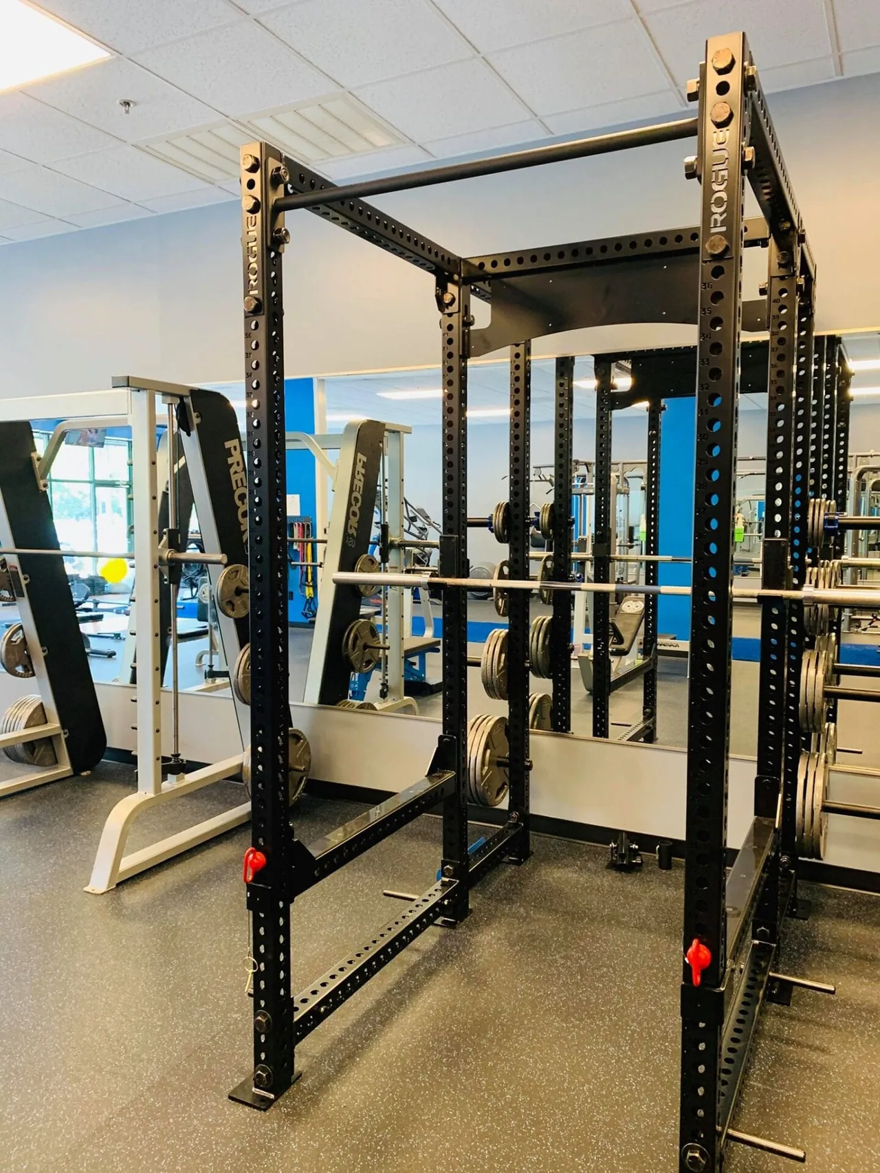 Black squat rack with hooks and safety arms set up for back squats.